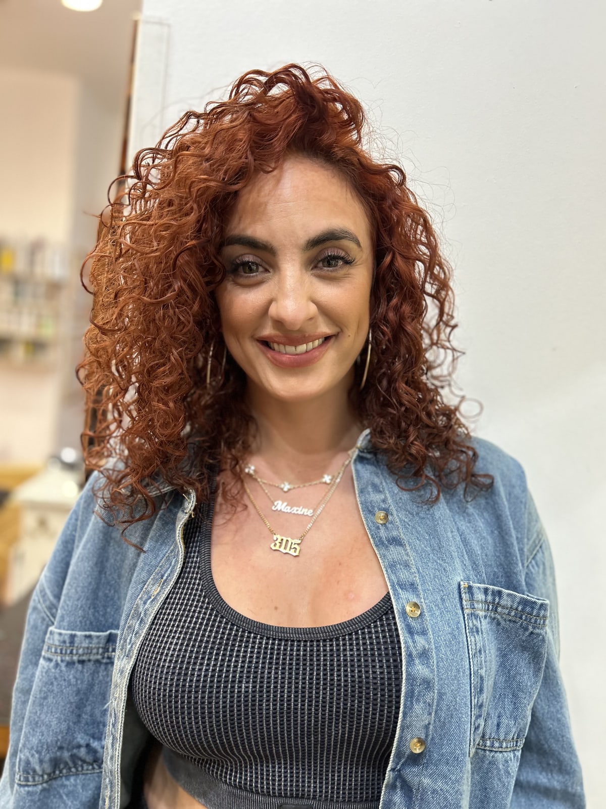 Client with defined copper curls, smiling after a curl appointment at Frenzy Salon