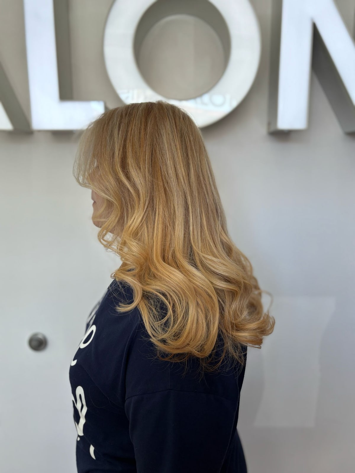 Long, softly waved blonde hair styled at Frenzy Salon
