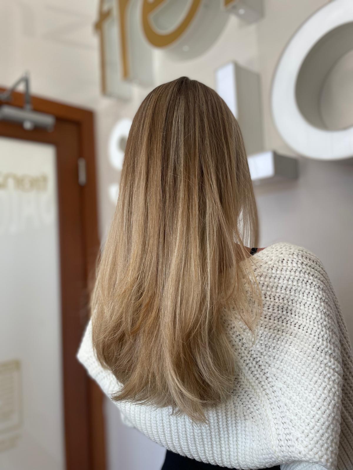 Back view of long honey-blonde hair with soft waves in the Frenzy Salon studio
