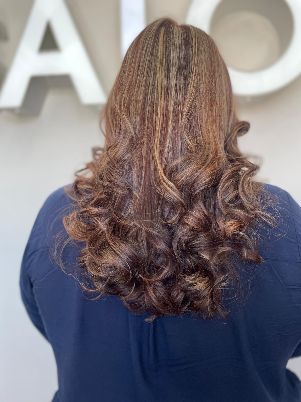 Warm honey highlights styled in soft waves at Frenzy Salon
